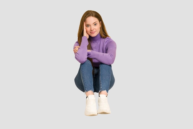 Young redhead woman sitting isolated cut out