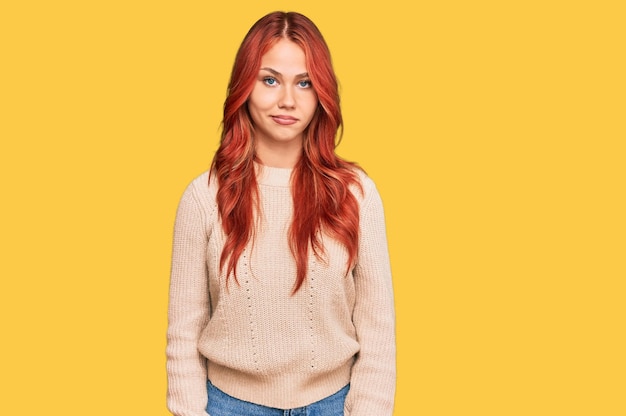 Young redhead woman wearing casual winter sweater looking sleepy and tired, exhausted for fatigue and hangover, lazy eyes in the morning.