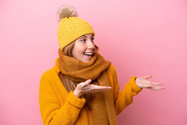 Young redhead woman wearing winter jacket isolated on pink background with surprise facial expression