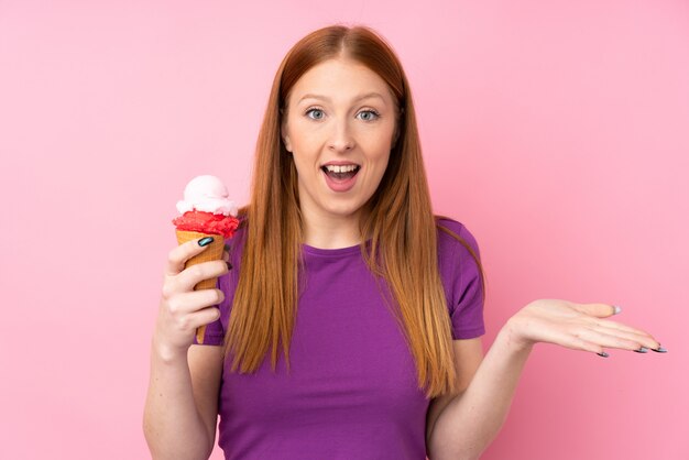 Young redhead woman with a cornet ice cream with shocked facial expression