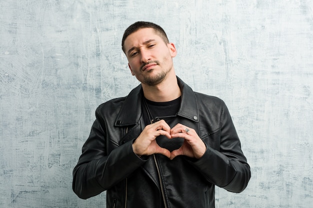 Photo young rocker man smiling and showing a heart shape with him hands.