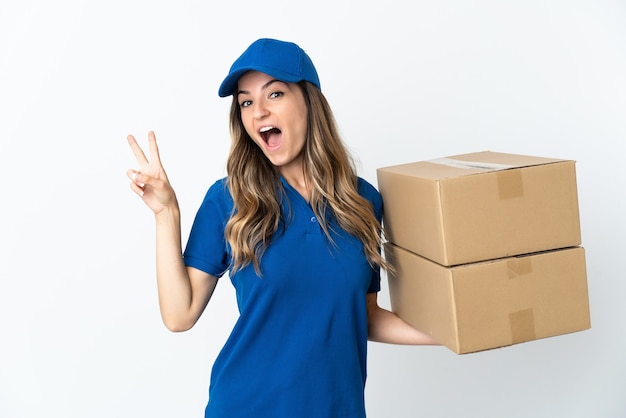 Young Romanian delivery woman isolates on white wall smiling and showing victory sign