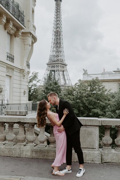 Photo young romantic couple spending their vacation in paris france dating couple posing near the eiffel