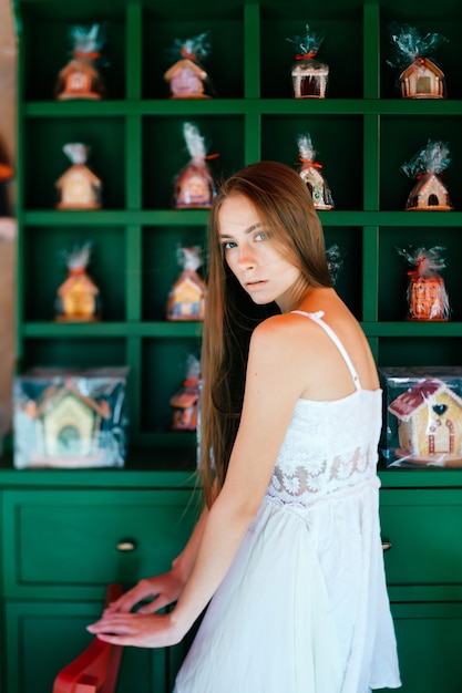 Young romantic elegant girl in white dress posing over decorated wall