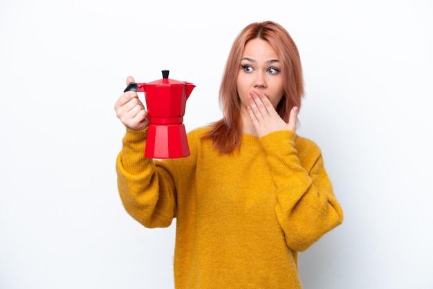 Young Russian girl holding coffee pot isolated on white background with surprise and shocked facial expression