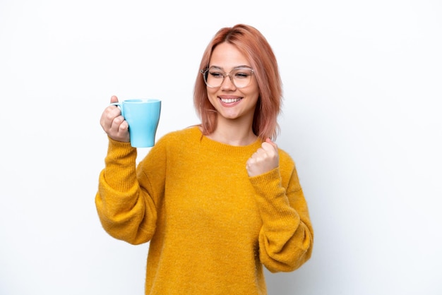 Young Russian girl holding cup of coffee isolated on white background celebrating a victory