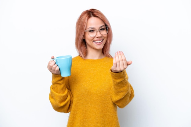 Young Russian girl holding cup of coffee isolated on white background inviting to come with hand Happy that you came