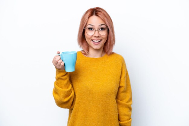 Photo young russian girl holding cup of coffee isolated on white background with surprise and shocked facial expression