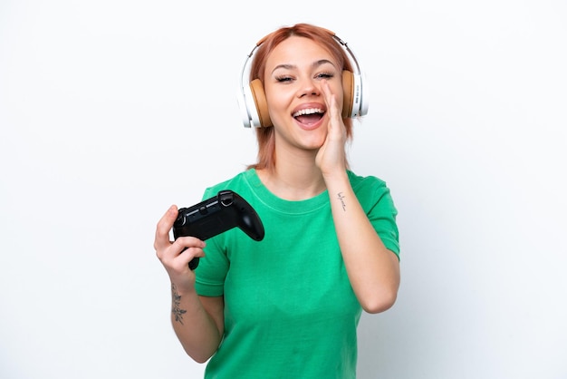 Young Russian girl playing with a video game controller isolated on white background shouting with mouth wide open