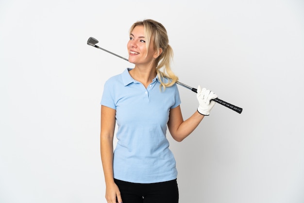 Young Russian golfer woman isolated on white wall looking to the side and smiling