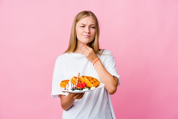 Young russian woman eating a waffle isolated suffers pain in throat due a virus or infection