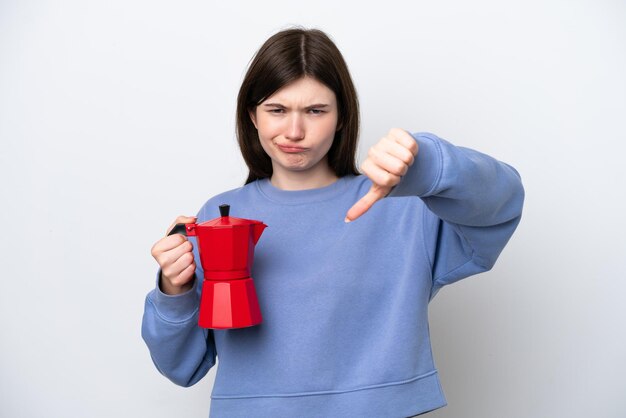 Young Russian woman holding coffee pot isolated on white background showing thumb down with negative expression