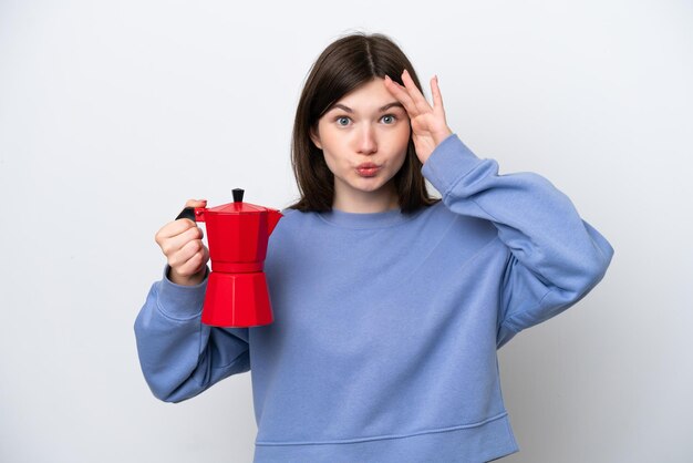 Young Russian woman holding coffee pot isolated on white background with surprise expression