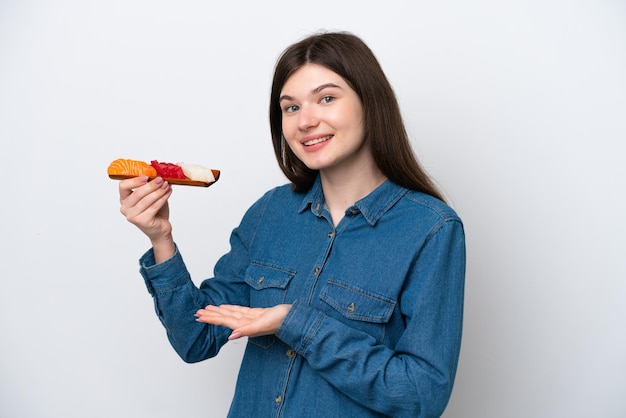 Young Russian woman holding sashimi isolated on white background extending hands to the side for inviting to come