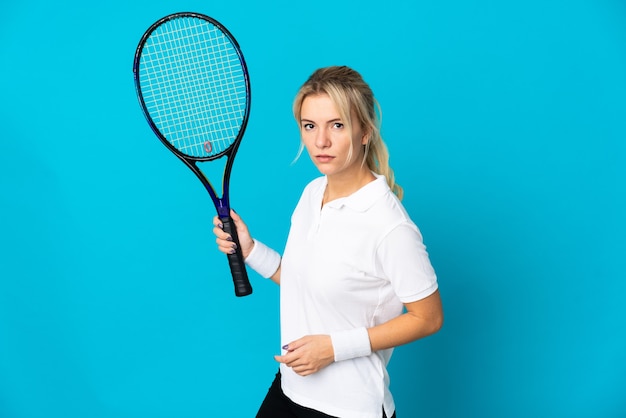 Young Russian woman isolated on blue background playing tennis