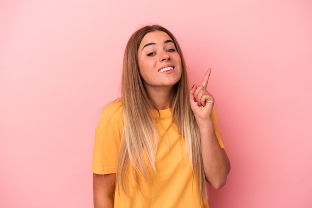 Young Russian woman isolated on pink background shocked and amazed holding a copy space between hands.