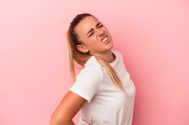 Young Russian woman isolated on pink background suffering a back pain.