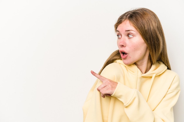 Young russian woman isolated on white background points with thumb finger away laughing and carefree