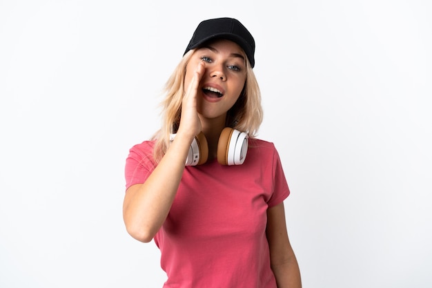 Young Russian woman listening music isolated on white shouting with mouth wide open