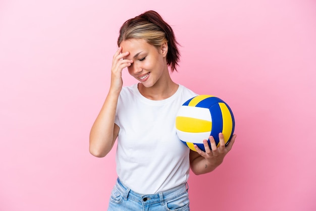 Young Russian woman playing volleyball isolated on pink background laughing