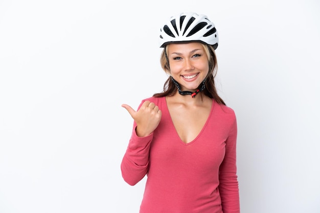 Young Russian woman wearing a bike helmet isolated on white background pointing to the side to present a product