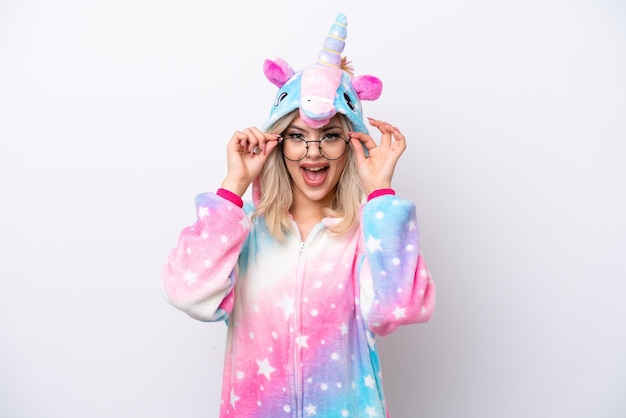 Young Russian woman with unicorn pajamas isolated on white background with glasses and surprised