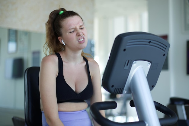 Young sad fat frustrated woman train at gym doing cardio exercise trying to lose weight and drink