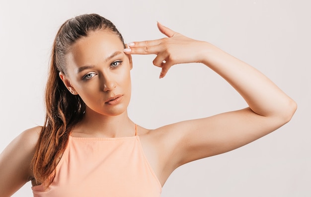 Young sad serious girl making gun gesture with hand over isolated gray background