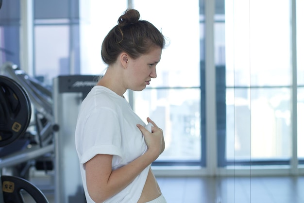 Young sad upset woman is disappointed because of fat belly stomach looking at mirror with frustrated