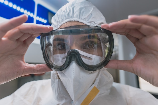 Young sanitary woman puts on a protective suit against viruses in an ambulance