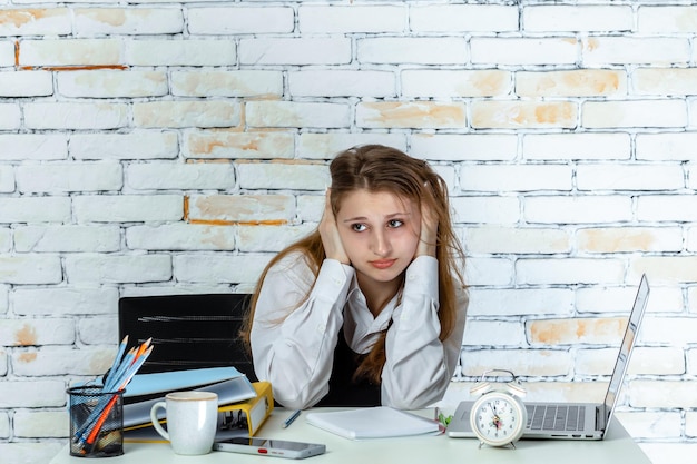 Young school girl sitting behind of desk and feeling tired