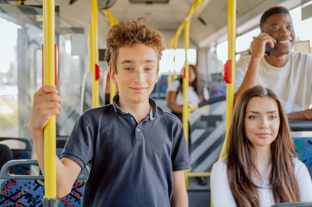 Young schoolage boy is riding public transport bus to elementary school holding phone in hand