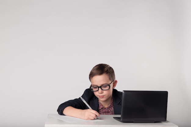 Young schoolboy in suit writing with pen