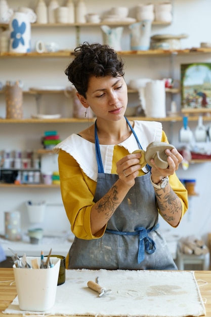 Young sculptor girl hold sponge shape jar in pottery workshop student learn to work with raw clay