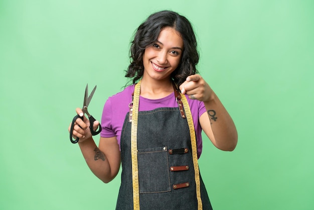 Young seamstress argentinian woman over isolated background pointing front with happy expression