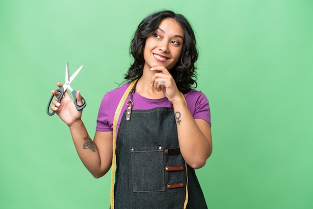 Young seamstress argentinian woman over isolated background thinking an idea while looking up