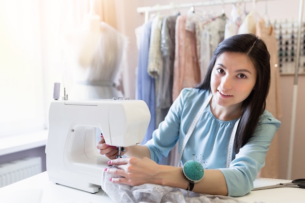 Young seamstress with sewing machine working at her office. Small business concept