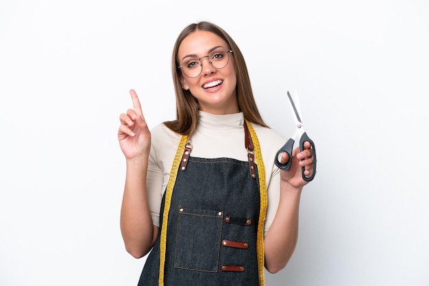 Young seamstress woman isolated on white background showing and lifting a finger in sign of the best