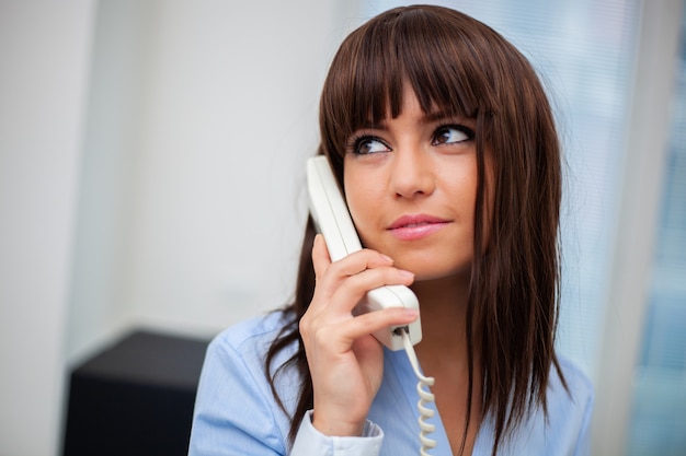 Young secretary on the phone in her office