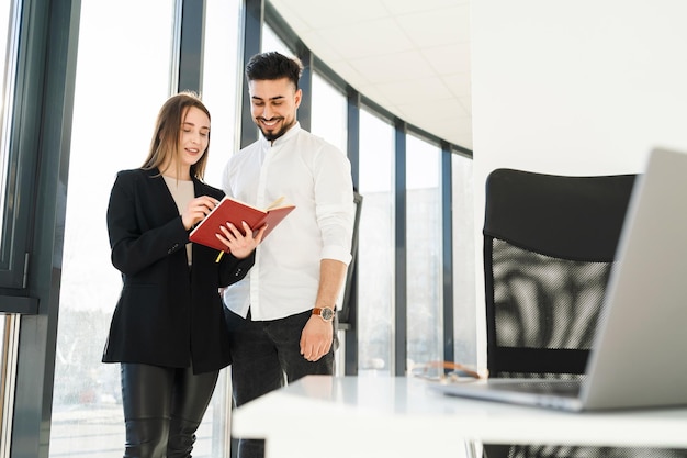 Young secretary shows her boss a notebook Two company employees in the office