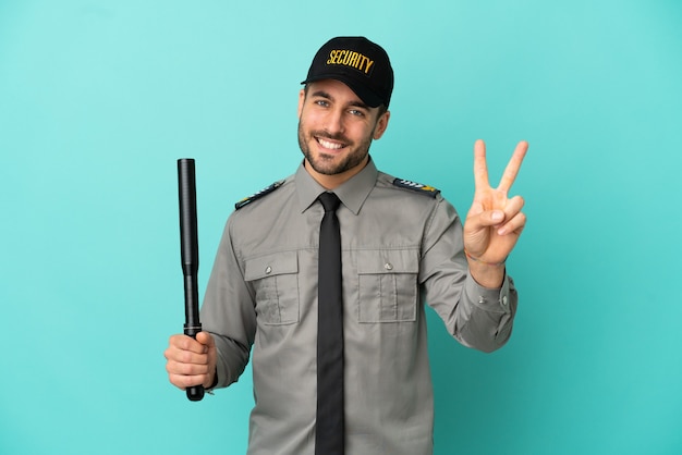 Young security man isolated on blue background smiling and showing victory sign