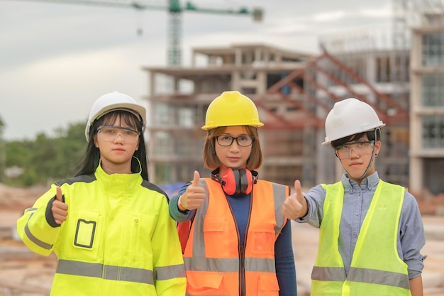 Young and senior Engineers discuss about work of large building underconstructionThree people working on site of under construction