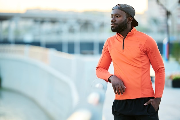 Young serene african american athlete in red sport jacket and black cap