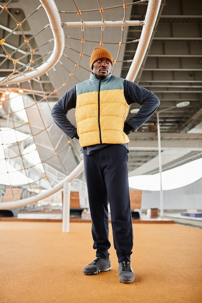 Young serious African American athlete standing on sports ground with facilities