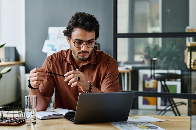 Young serious businessman in shirt and eyeglasses networking