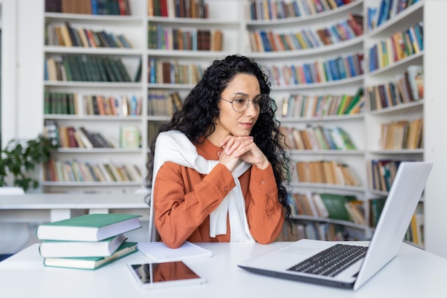 Young serious female student thinking about a solution to an assignment studying remotely while