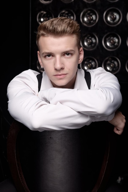 Young serious man on chair, close-up portrait, fashion model