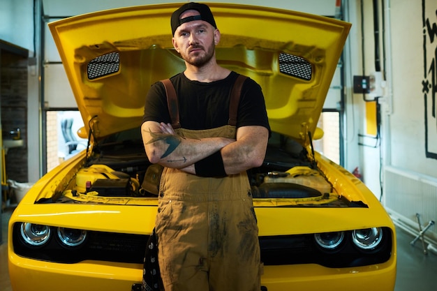 Young serious workman in overalls blackc tshirt and baseball cap