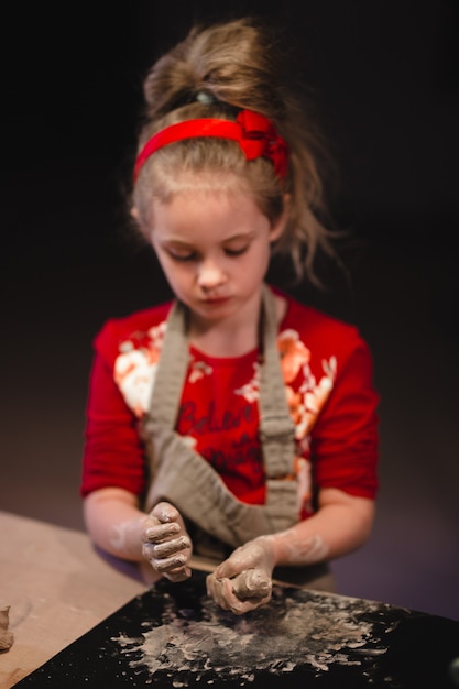 Young seven years old girl in pottery workshop creating a bowl from clay. Pottery workshop for kids.