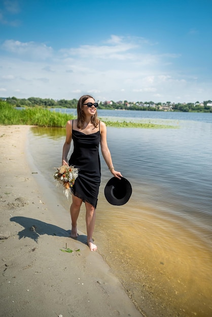 Young sexy woman in black dress walking of the lake